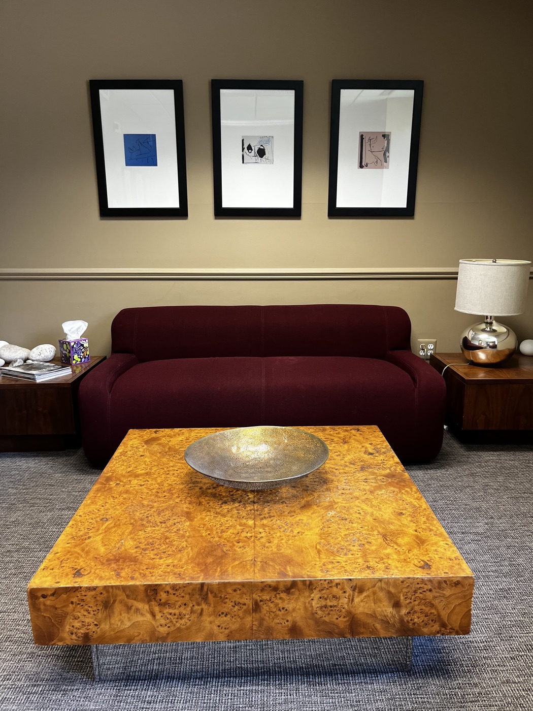 Therapy office with a deep red sofa and framed prints