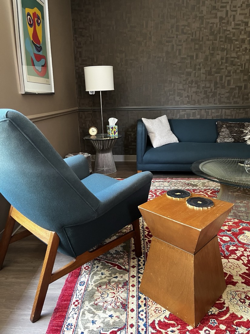 Therapy office with two teal armchairs, a sofa, and a patterned rug